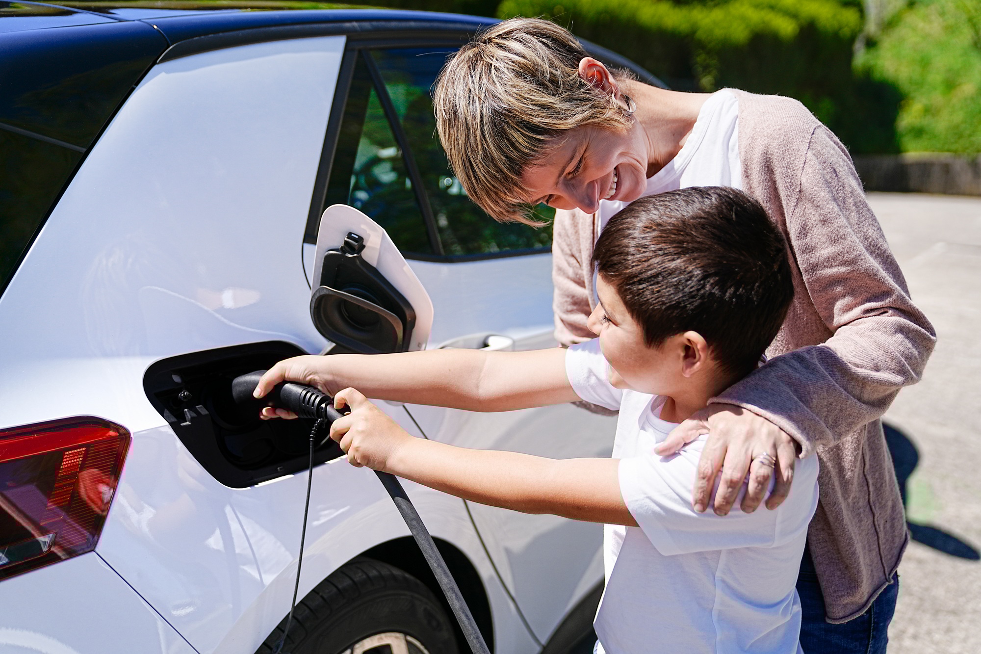 Mother and Son's Playful Collaboration at EV Charging Station